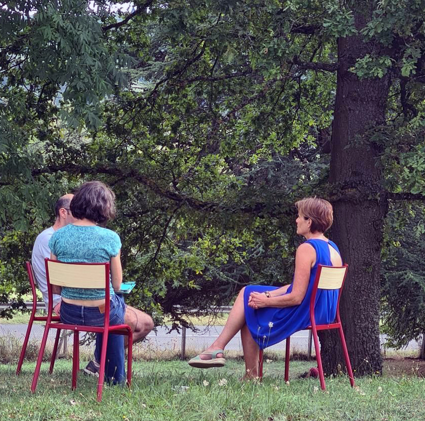 Des personnes en train de discuter à l'extérieur sur des chaises